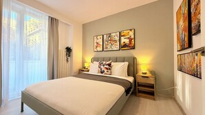 Een moderne slaapkamer met een groot bed, nachtkastjes en abstracte wanddecoratie.