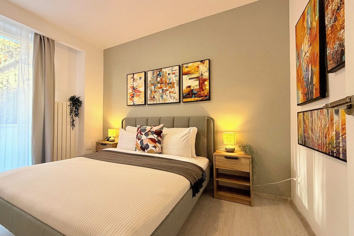 Ein modernes Schlafzimmer mit einem großen Bett, Nachttischen und abstrakter Wandkunst.