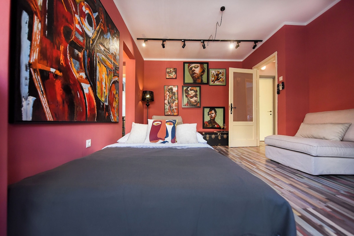 Ein Schlafzimmer mit einem Bett, einer Couch und verschiedenen Kunstwerken an den Wänden.