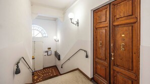 Una scala con ringhiera, una porta in legno e un punto luce a parete.