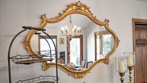 Une pièce dotée d’un grand miroir décoratif, d’un lustre et d’une porte en bois.