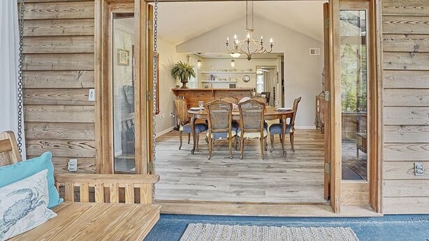 L’intérieur d’un chalet en bois comprend un coin repas, un lustre et une grande fenêtre.
