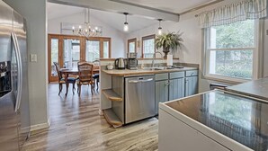 Une cuisine moderne dotée d’un îlot central, d’appareils électroménagers en acier inoxydable et d’un coin repas avec des chaises en bois.