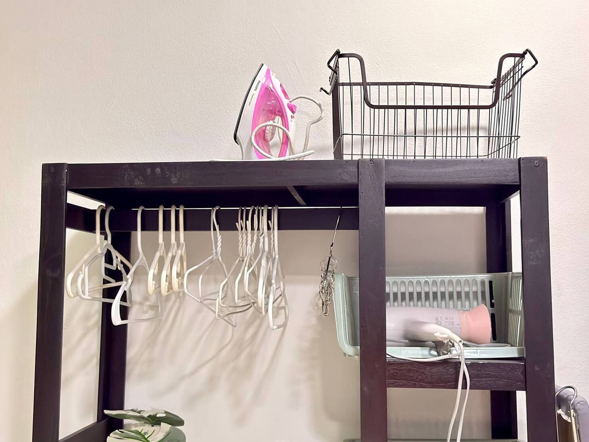 A dark wooden shelf unit with multiple hooks for hanging items, a small basket, and a radiator.