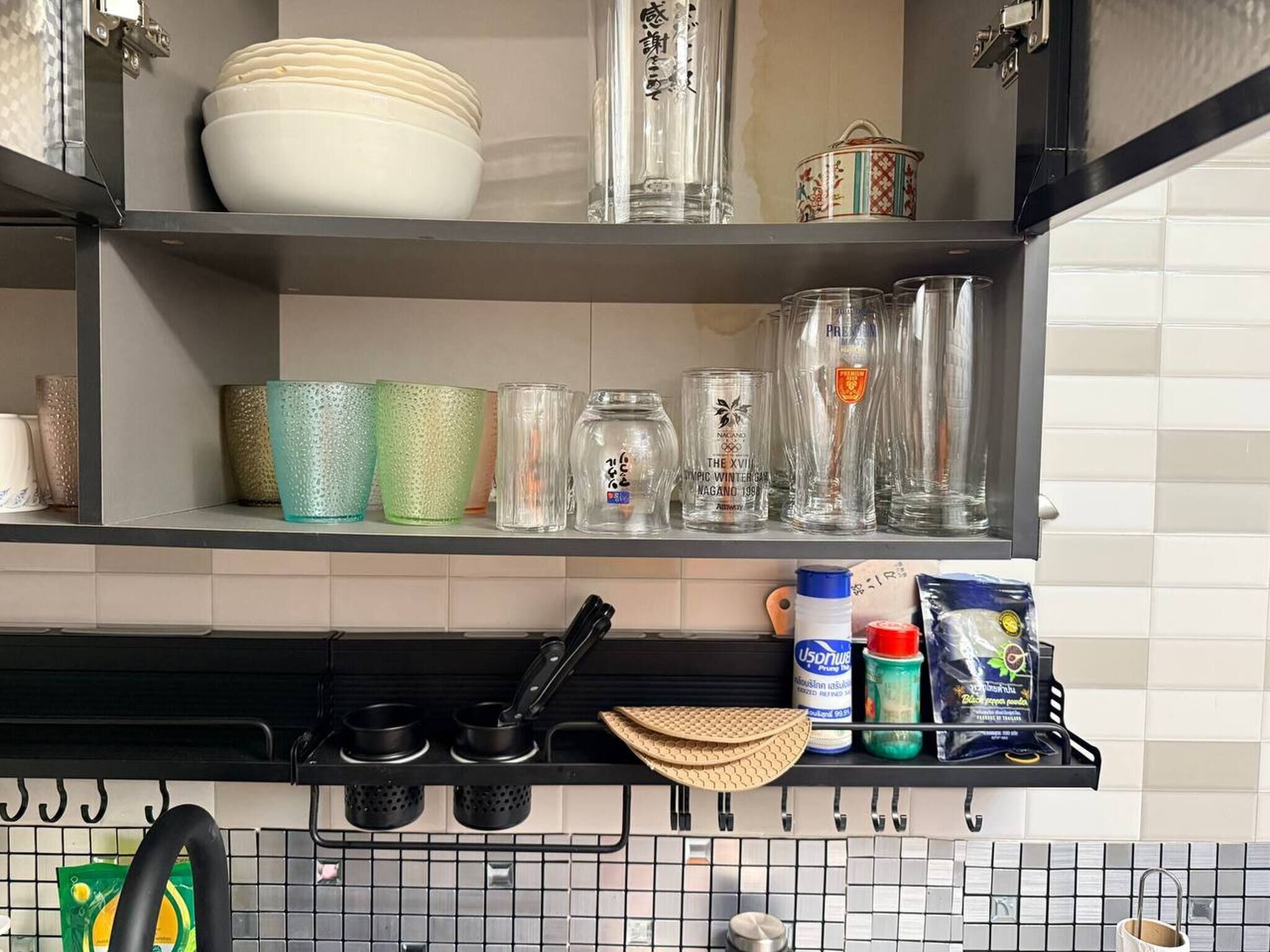 A kitchen with shelves holding dishes, glasses, and kitchen utensils.