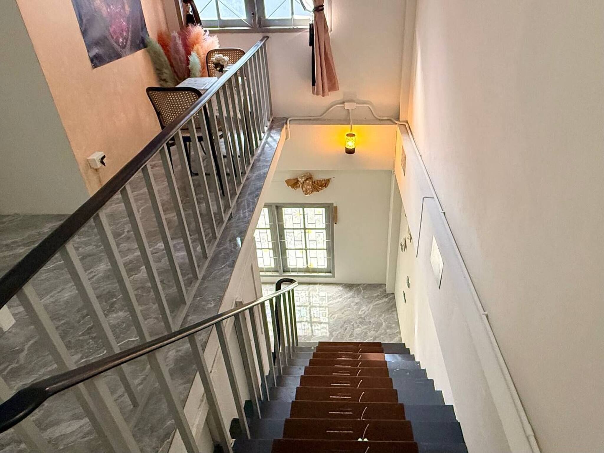 A staircase with a handrail, a wall-mounted light, and a window with blinds.