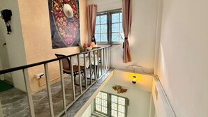 A staircase with a railing, a dining area with a table and chairs, a large floral painting on the wall, and a window with curtains. - Heaven of Pattaya, Entire Private 2 Floors, 3 Bedrooms for big Families! (Pattaya)