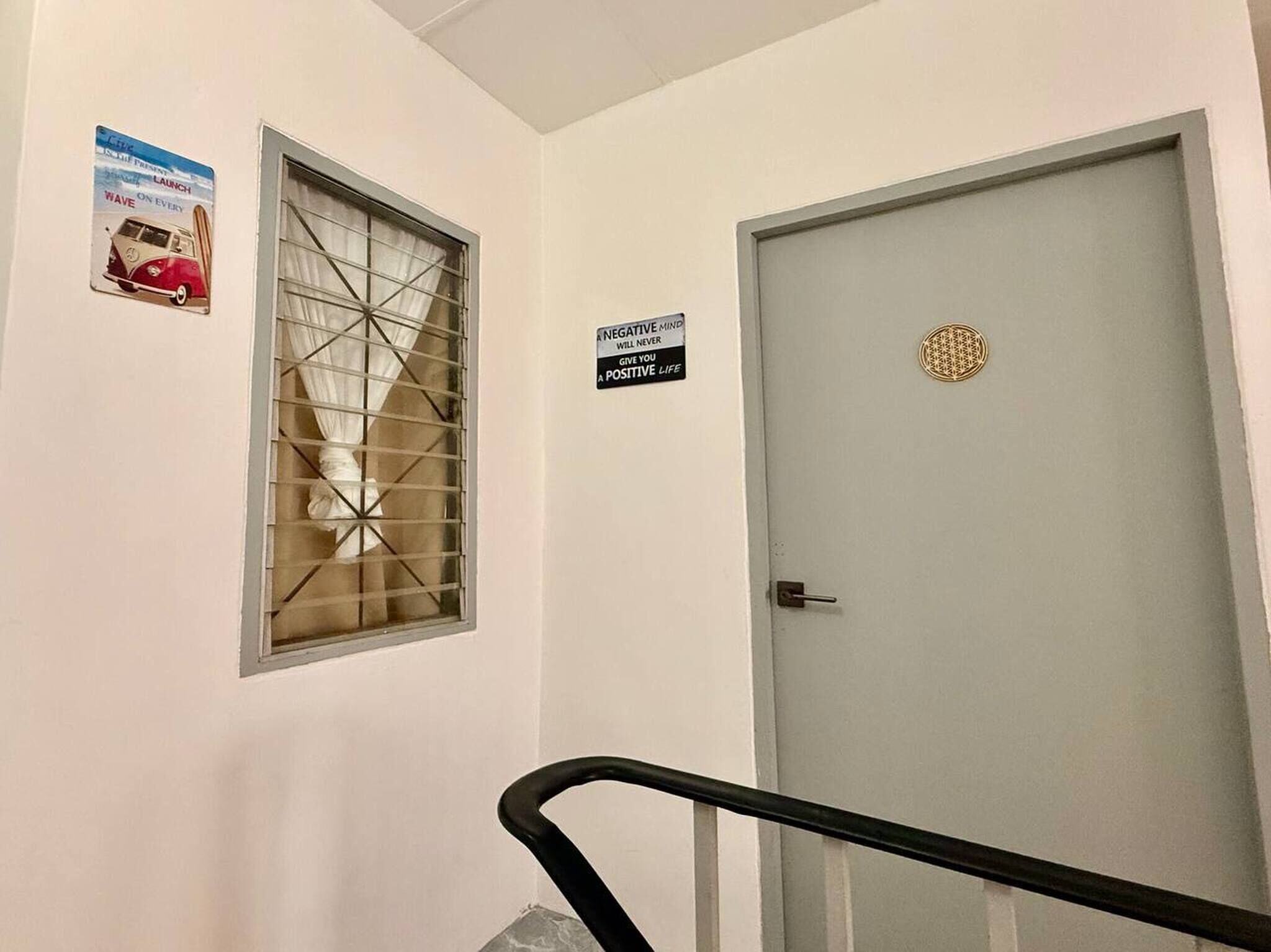 A hallway with a window, a door with a decorative emblem, and a sign on the wall.