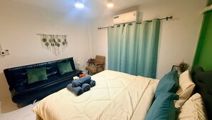 A bedroom with a bed, a chair, a sofa, an air conditioner, and a wall-mounted fan. - Heaven of Pattaya, Entire Private 2 Floors, 3 Bedrooms for big Families! (Pattaya)