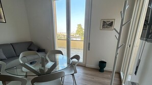 Een moderne keuken met een eethoek, een kapstok en uitzicht door de glazen deur.