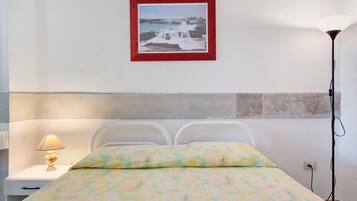 A bedroom with a bed, a nightstand, a lamp, and a framed picture on the wall.