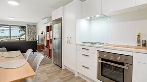 Una cucina moderna con mobili bianchi, forno integrato e zona pranzo con tavolo e sedie.