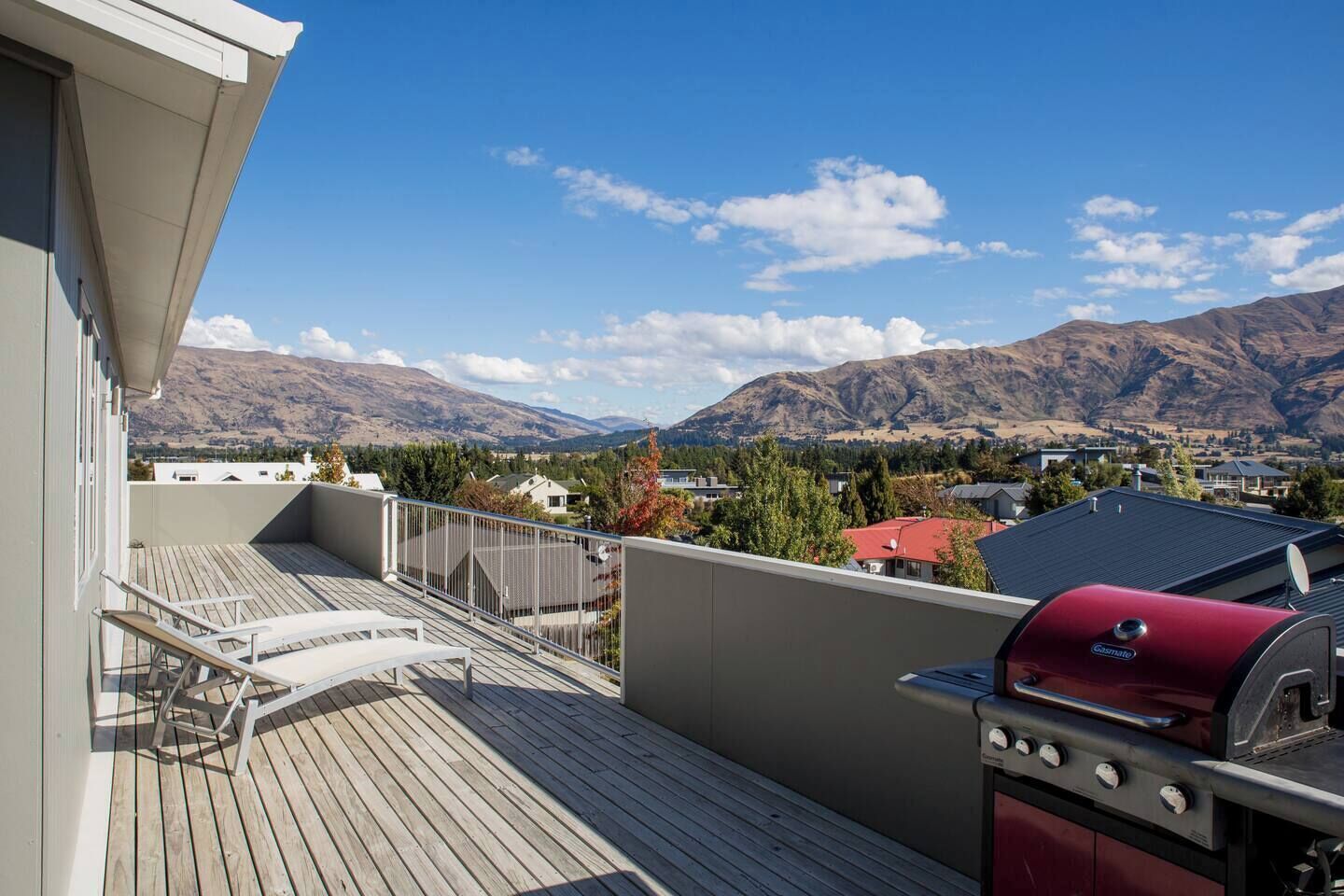 Ein Balkon mit Blick auf Berge, einem Grill und einer Sitzecke.