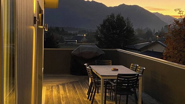 Un balcone con tavolo e sedie, un barbecue e vista sulle montagne.