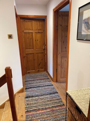 A wooden door with a textured carpet leading to a room.