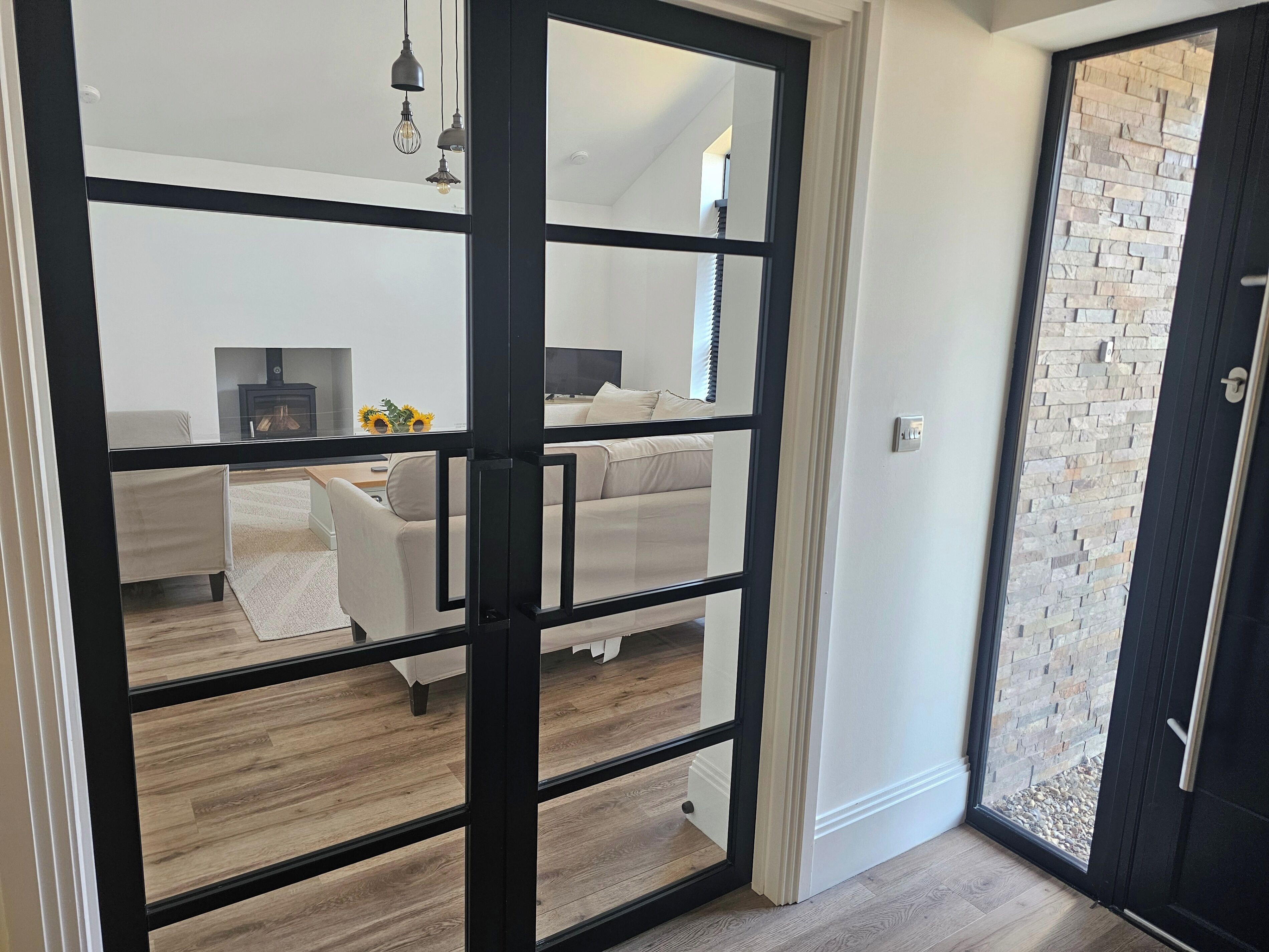 A modern interior with a glass door leading to a living area featuring a sofa, a coffee table, and a fireplace.
