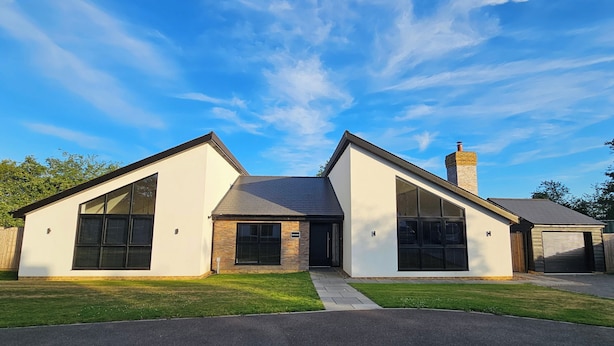 A modern two-story house with a large front window, a chimney, and a garage. - Luxury Kent Bungalow Retreat Sleeps 12 (Tonbridge)