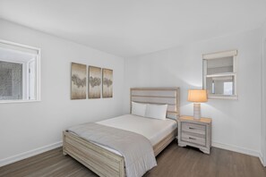 A bedroom with a bed, bedside table, lamp, and wall art. - Luxury 3BR Beachfront Condo - Wrap Balcony, Endless Gulf Views! Pool & Beach! (Miramar Beach)
