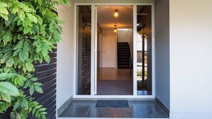 A modern entrance with a sliding glass door, a staircase, and a hanging light fixture. - Wanaka 'Mount Iron Edge' with Mountain Views (Wanaka)