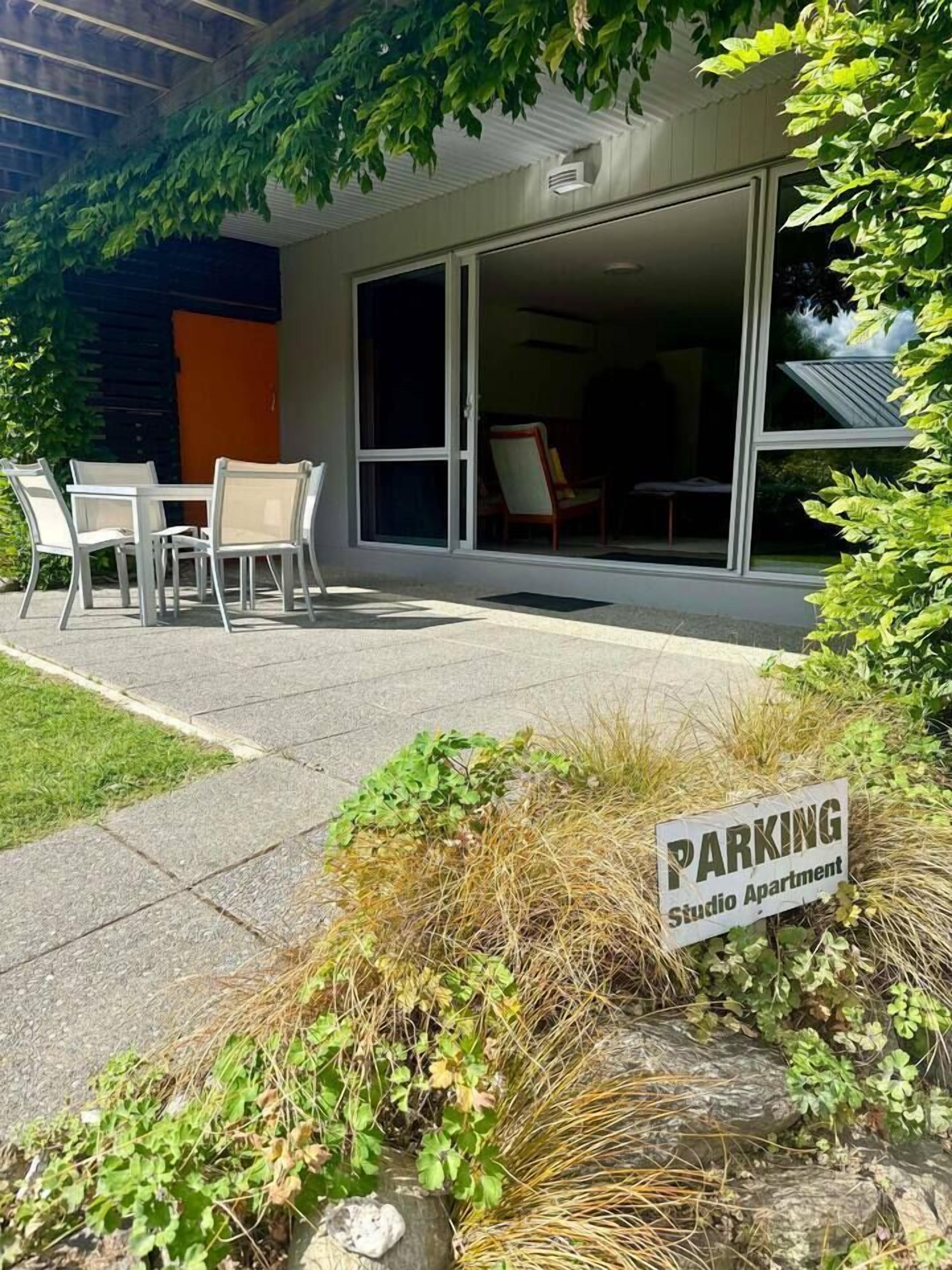Een studio-appartement met een patio, een bord met daarop parkeergelegenheid, en een uitzicht op de gevel van het gebouw.
