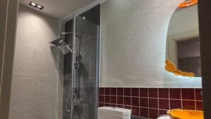 Un baño moderno con ducha de vidrio, inodoro blanco y lavamanos con lavabo amarillo.