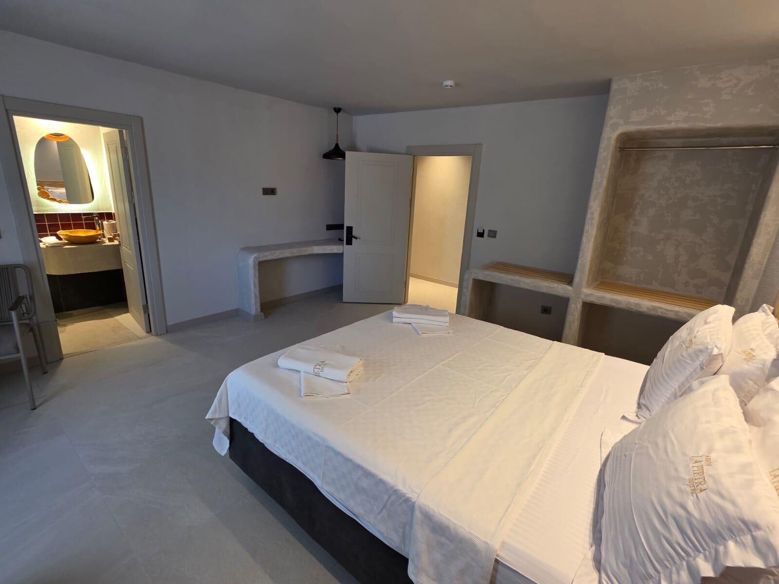 Une chambre à coucher avec un lit, un bureau, une chaise et un miroir.