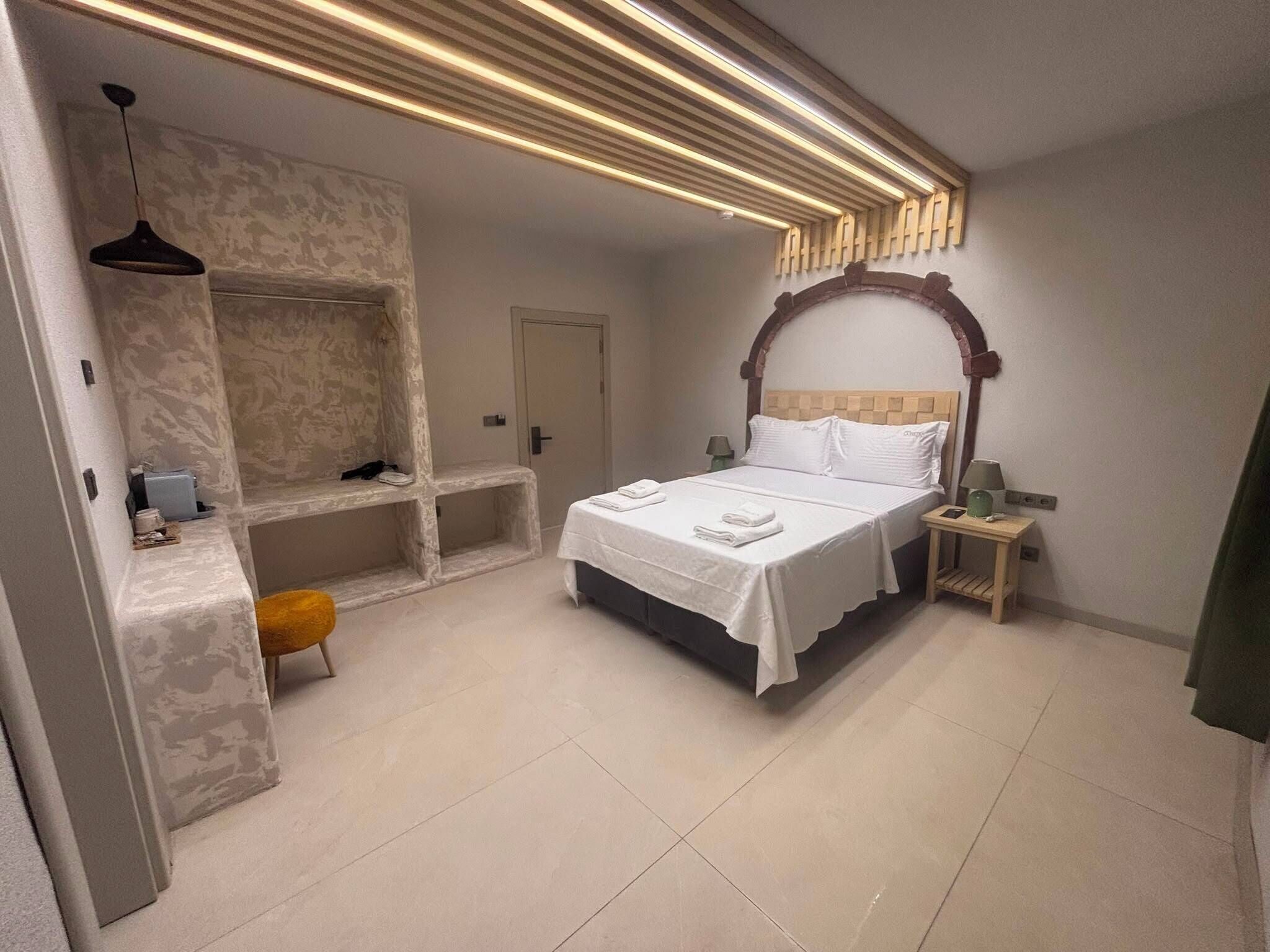 A modern bedroom with a large bed, a built-in bench, and a unique ceiling light design.