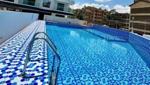 A swimming pool with blue mosaic tiles, surrounded by high-rise buildings. - Capital Rise View Palace Apartment (Nairobi)
