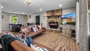 Una sala de estar con chimenea, televisor y comedor.