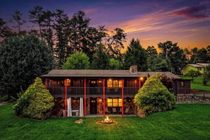 A two-story building with a stone facade, multiple windows, and a fire pit in the front yard. - Family Retreat: 3BR Cabin w/ Game Room, Mountain Views & Free Attractions (Sevierville)