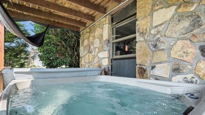 Un jacuzzi de paredes de piedra con una pérgola de madera arriba.