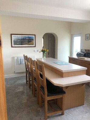 A modern kitchen with a central island, wooden chairs, a radiator, and a framed picture on the wall. - PANORAMIC views in the heart of the Lakes, Keswick (Portinscale)