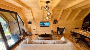 Un acogedor interior de cabaña con sofá, mesa de comedor, sillas, televisor y chimenea.