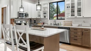 Een moderne keuken met witte kasten, een centraal eiland en uitzicht op de omgeving.