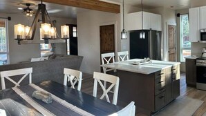 Een moderne keuken met een centraal eiland, witte kasten en hanglampen.