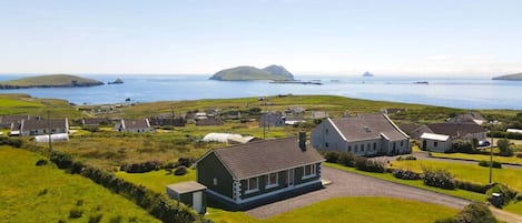 A coastal village with houses, a grassy area, and a view of the sea.