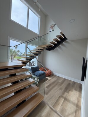 A modern interior with a wooden staircase, a glass railing, and a view of the outdoors. - Coastal Luxury Villa: Private Pool, TV Patio (Mexico Beach)