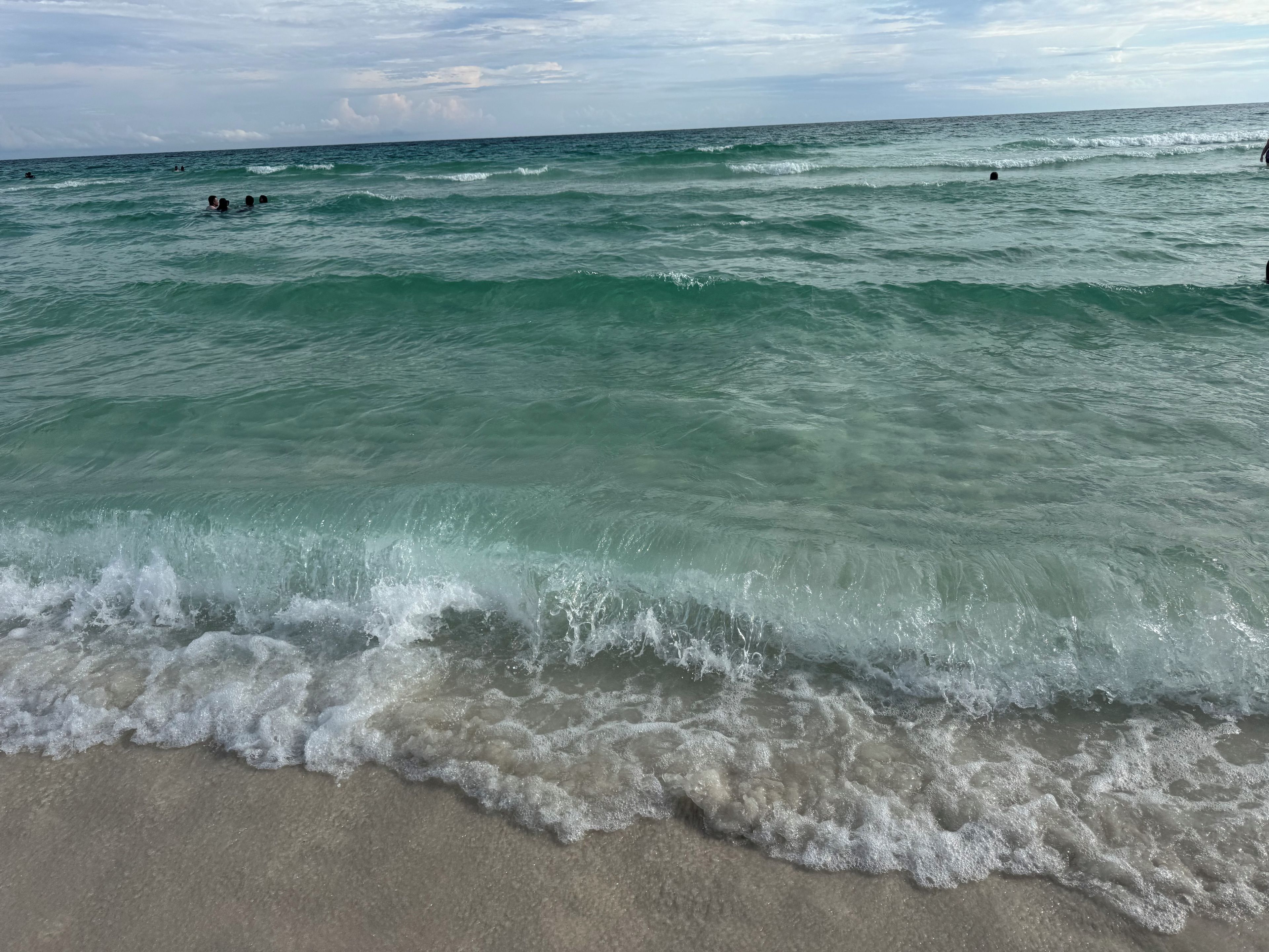 A beach with waves and people swimming.