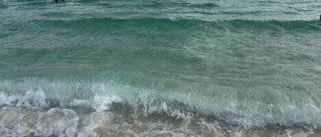 A beach with waves and people swimming.