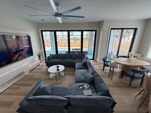 A living room with a sectional sofa, a coffee table, a TV, and a ceiling fan. - Coastal Luxury Villa: Private Pool, TV Patio (Mexico Beach)