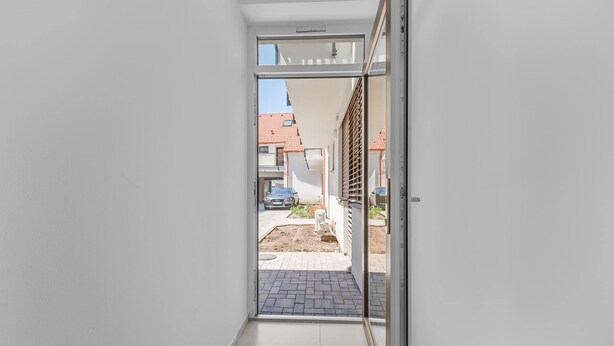 A narrow hallway leading to an outdoor area with a car parked outside.