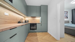 A compact kitchen with a wooden countertop, built-in oven, and grey cabinets.