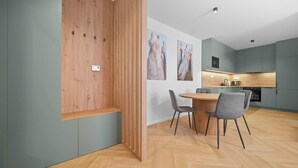 A modern kitchen with a wooden partition, a dining area with a round table and chairs, and artwork on the wall.