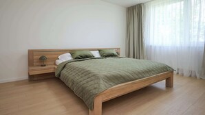 A bedroom with a wooden bed, a nightstand, and a lamp.