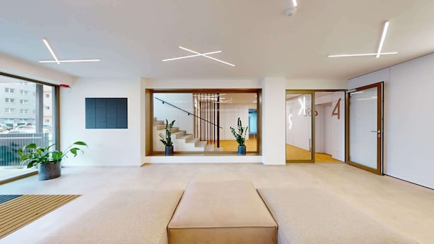 Een modern interieur met een trap, een plant en uitzicht op buiten.