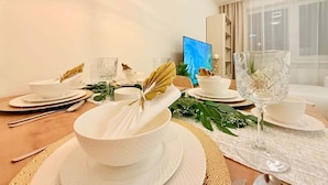 Een eettafel gedekt met witte servies, een glas en een schaal met een bladdecoratie.