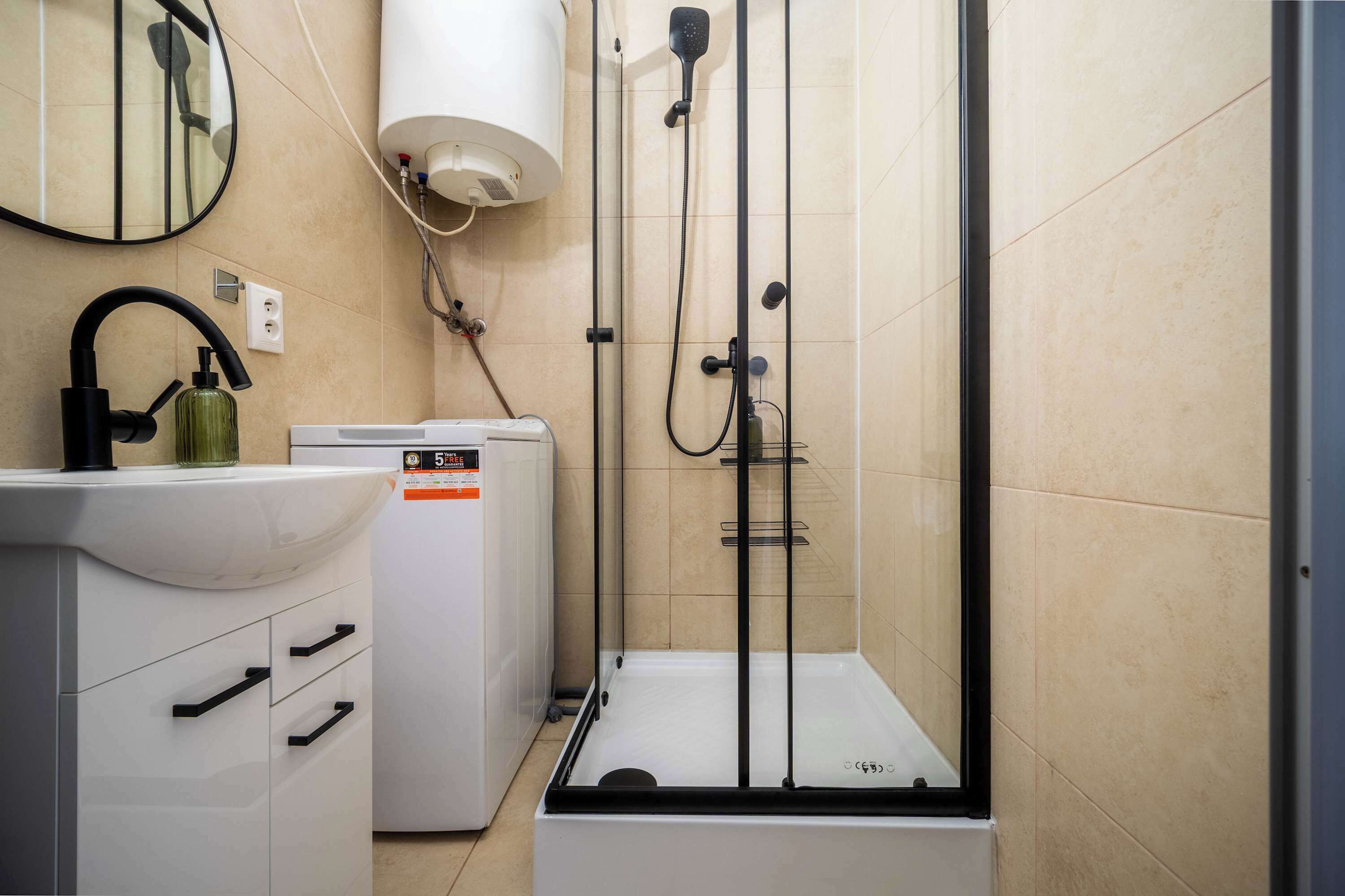 Ein Badezimmer mit Waschbecken, Spiegel, Handtuchhalter und Duschkabine.