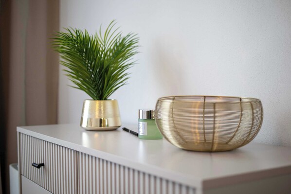 A white cabinet with a plant and a container on top.