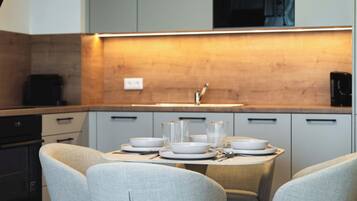A modern kitchen with a dining table set for four, equipped with white plates, bowls, and glasses.
