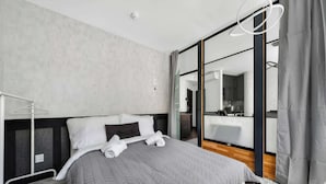 Et moderne hotelværelse med en stor seng, et natbord, et spejl og udsigt til badeværelset.